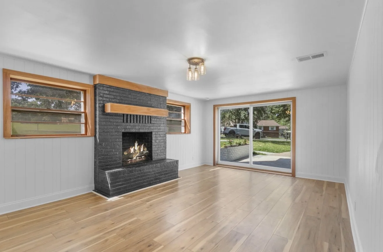 Completed bright interior with dark brick fireplace, natural wood accents and wood-look flooring