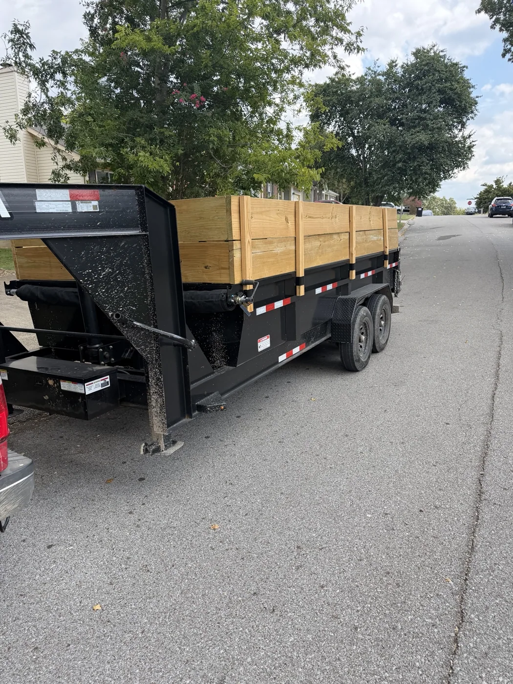 Black tandem axle dump trailer with wooden side extensions