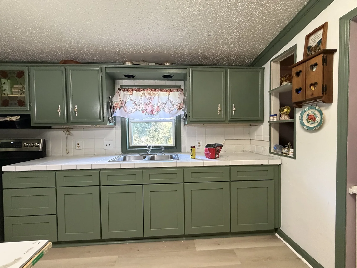 Completed kitchen with green cabinets, light wood-look flooring and tiled countertops